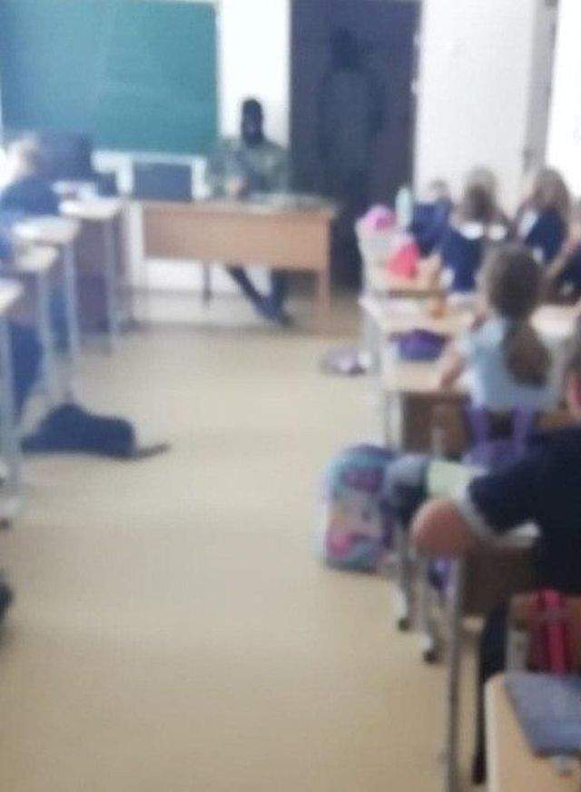 Мужчина стоит на подоконнике в классе