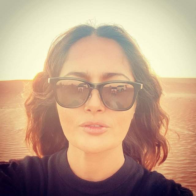 Сальма Хайек в очках и черной кофте в пустыне