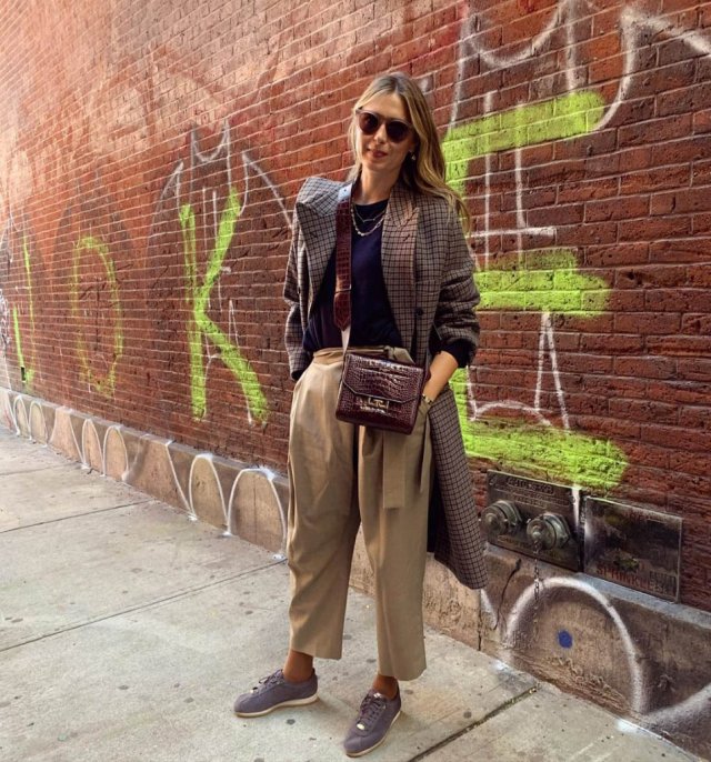 Мария Шарапова в коричневом костюме на фоне кирпичной стены