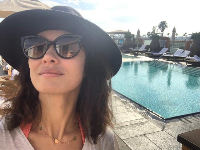 Ольга Куриленко в черных очках и шляпе около бассейна