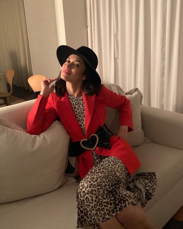 Ольга Куриленко в леопардовом платье и красном пиджаке на диване