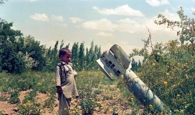 Афганский мальчик смотрит на неразорвавшеюся бомбу