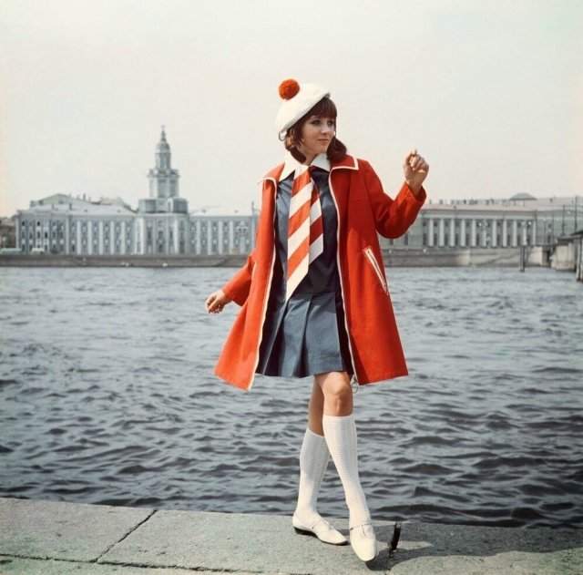 Девушка на набережной в Петербурге в красном пальто, синем платье и галстуке в полоску