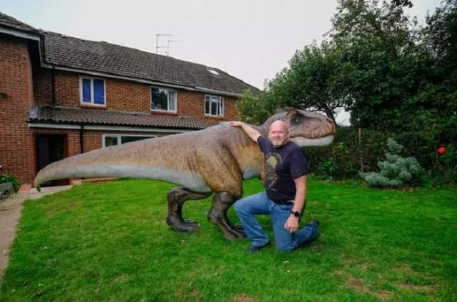 Хозяин дома и фигура тираннозавра в саду