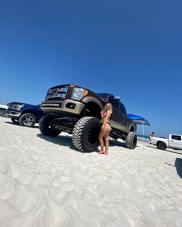 Девушка позирует у пикапа на песке