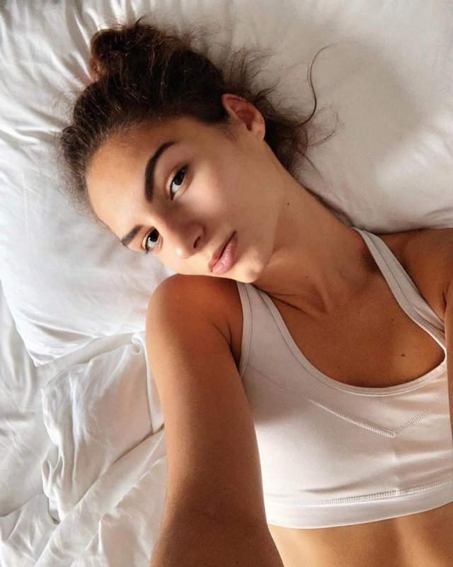 Анастасия Бадина на кровати в белом топе