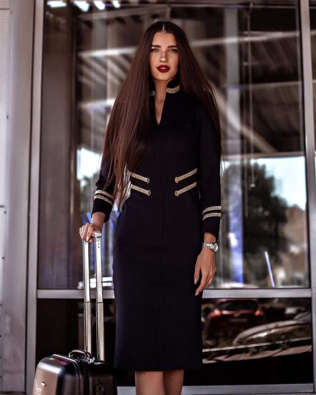 Стюардесса Алена Глухова в форме с чемоданом выходит из аэропорта
