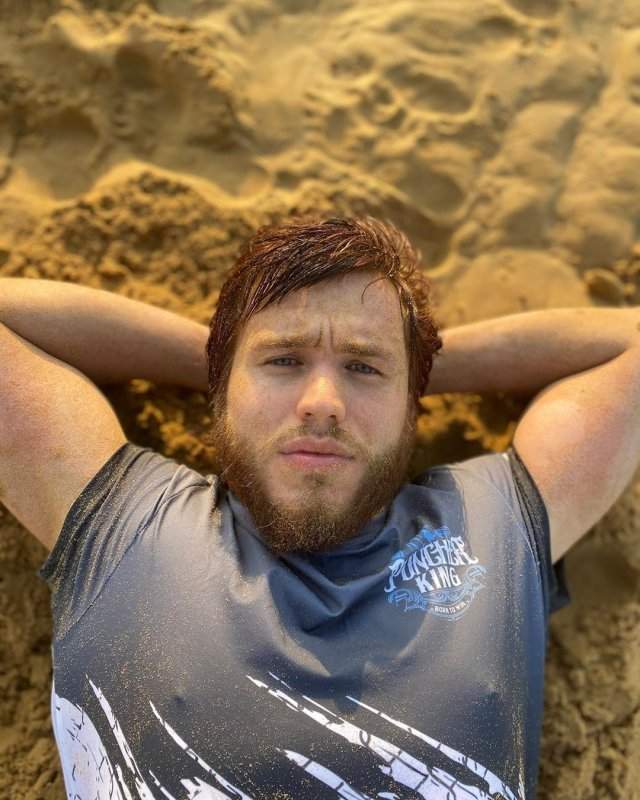 Сергей Романович с бородой в футболке на песке