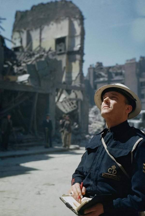 Смотритель ПВО проводит инспекцию поврежденных зданий в Холборне, Лондоне. 1941 г.