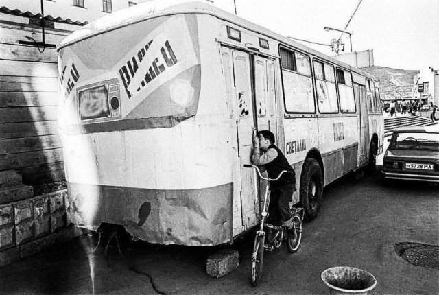 Мальчик подсматривает за показом фильма в видеосалоне, который находится в автобусе. Магадан, 1994 год.