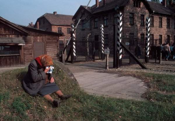 Женщина плачет у ворот музея концлагеря Аушвиц