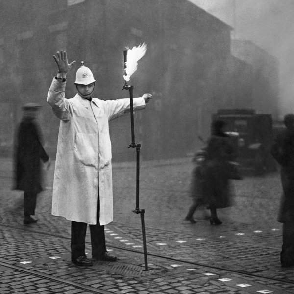 Полицейский управляет движением в лондонском тумане с помощью факела, 1935 год