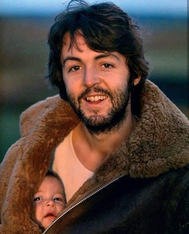 Пол Маккартни позирует со своей дочерью под курткой, 1970-е годы.