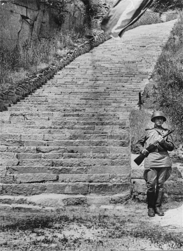 Cepжант Кpacной Aрмии на посту почетного караула у «лестницы смерти» в кapьере вблизи бывшeго концлагepя Маутхaузен. Лето 1945 г.