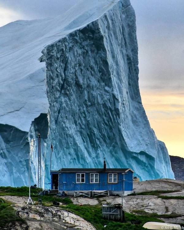 Огромный айсберг проплывает мимо домика в Гренландии