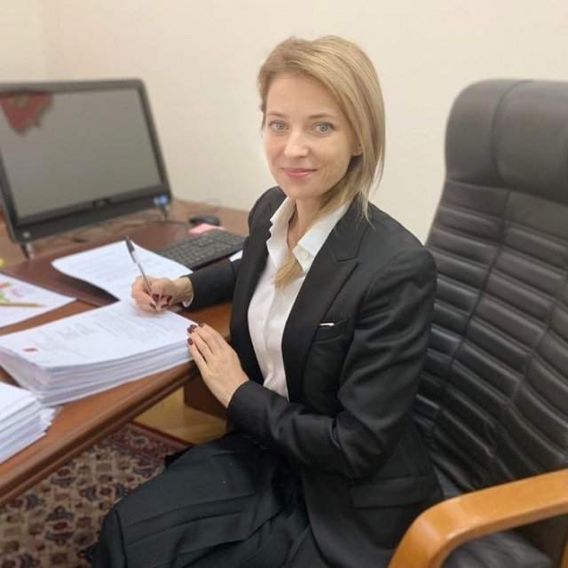 Политик Наталья Поклонская в черном пиджаке и белой рубашке за работой