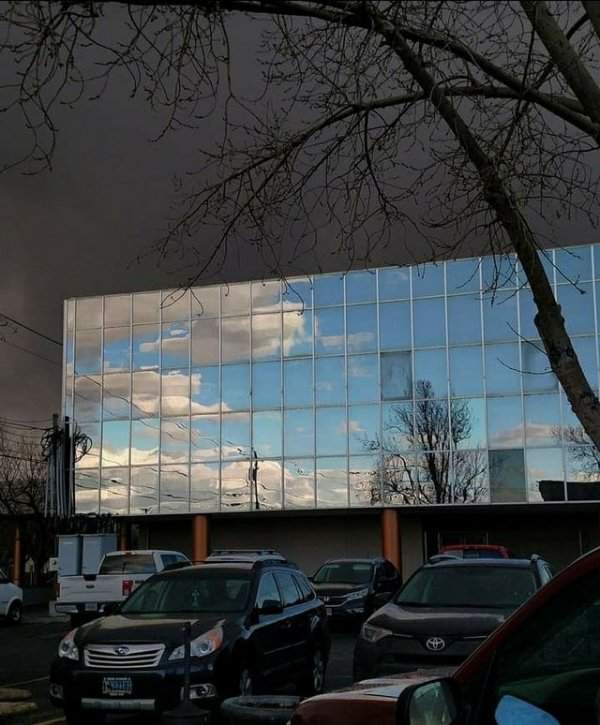 Голубое небо отражается в здании, а за ним гроза