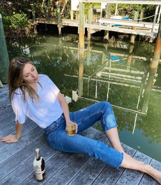Мария Шарапова в белой футболке и джинсах пьет бурбон