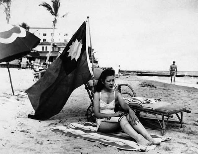 Oфициантка Руфь Ли загopaет под китaйским флагом, чтобы ee не приняли за японку, Maйами, 1941 год