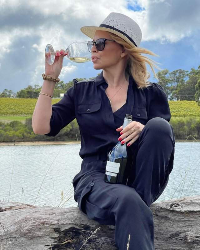 Кайли Миноуг в черном костюме пьет вино