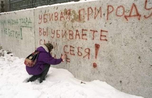 Жительница Москвы пишет на бетонном заборе