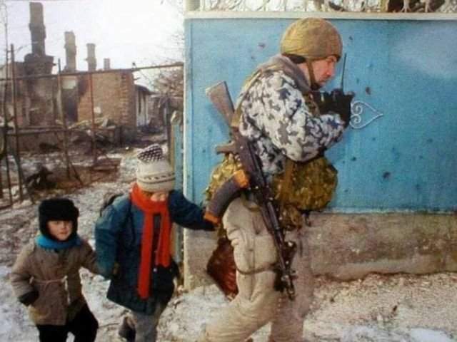 Боец ОМОНа ведёт обнаруженных в подвале дома детей к БТР. Грозный, февраль 1995 год.