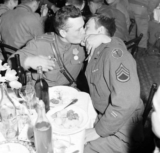 Советский офицер целует американского сержанта в ресторане в знак дружбы, 1945 год.