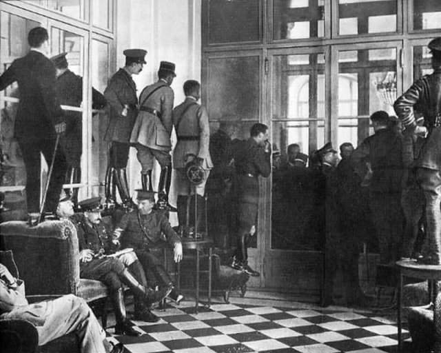 Люди стоят на кушетках, столах и стульях, чтобы увидеть подписание Версальского договора, официально завершившего Первую мировую войну, 1919 год.