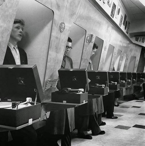 Посетители музыкальных магазинов прослушивают пластинки в специальных «примерочных». Лондон, 1955 год
