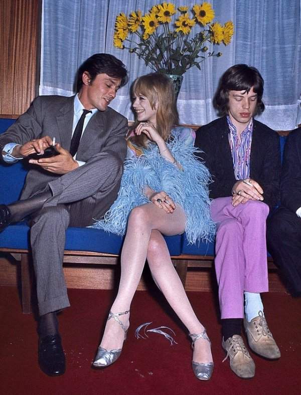Ален Делон весело общается с Марианной Фейтфулл, девушкой Мика Джаггера, а тот грустно сидит рядом, 1968 год