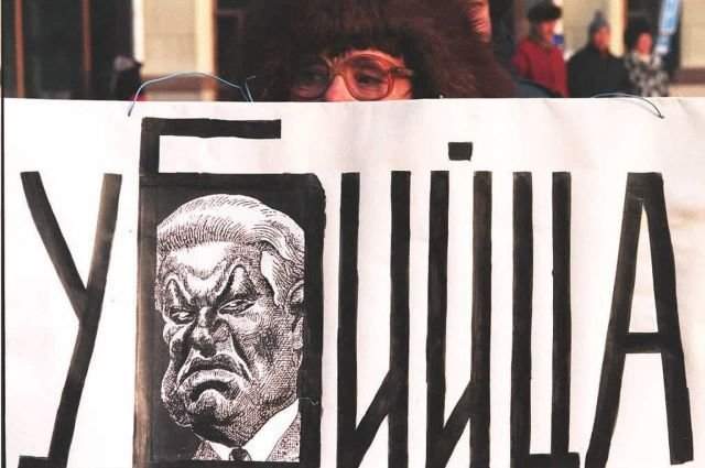 Женщина держит плакат с карикатурой на президента России Бориса Ельцина
