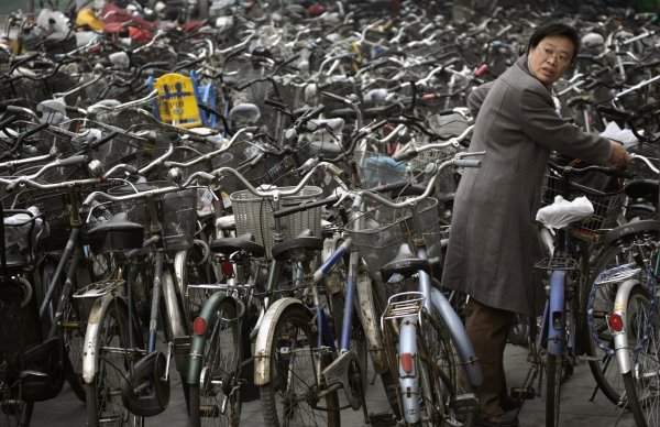 Женщина забирает свой велосипед на стоянке за станцией метро в Пекине