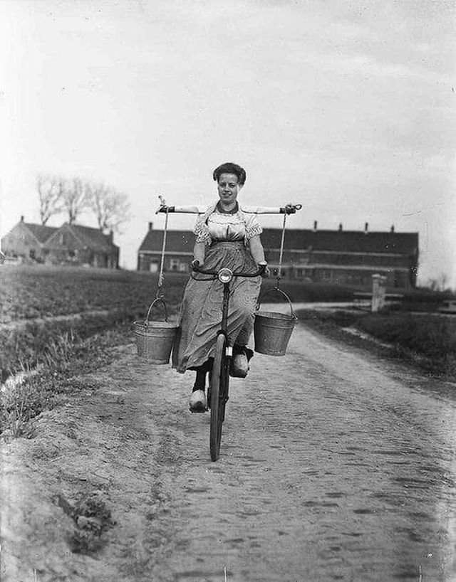 Крестьянка с ведрами молока на коромысле на велосипеде. Нидерланды, 1946 г.