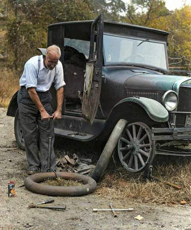 Мужчина меняет шины на Ford Model T Coupe 1927 года выпуска
